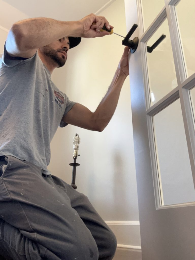 Image of a man fixing a door lock.